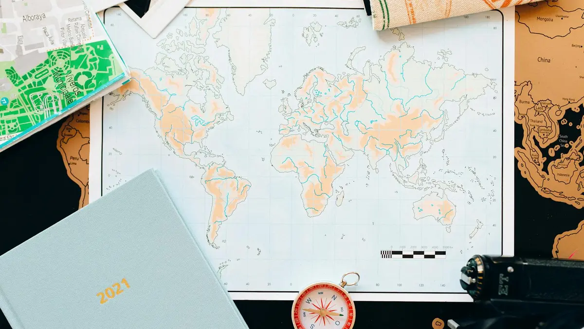 Mapa del mundo sobre mesa con calendario y agenda para planificar las mejores fechas de viaje
